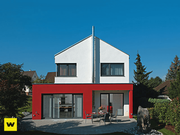 Modernes Einfamilienhaus mit roter Fassade, großen Fenstern und Garten im Wohngebiet.