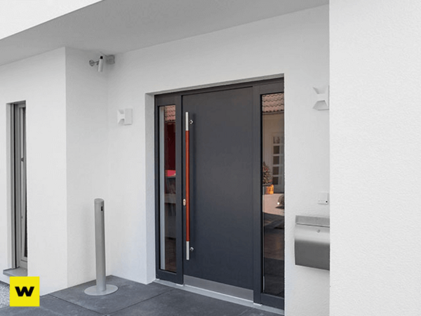 Moderne Haustür aus Aluminium mit Seitenteil in einem weißen, minimalistischen Eingangsbereich.